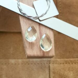 The pair of pale yellow citrine teardrops displayed on a jewellers bench peg with some sterling silver sheet and wire.