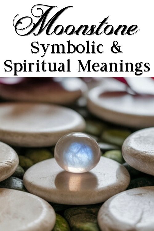 A luminous moonstone rests on smooth, white stones, capturing natural light. Bold black text above reads "Moonstone Symbolic & Spiritual Meanings."